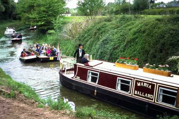 Narrowboat “Maria Ballard” leading a flotilla of smaller boats in 1995 approaching Monksbury Court Bridge on the Hereford and Gloucester Canal at Monkhide